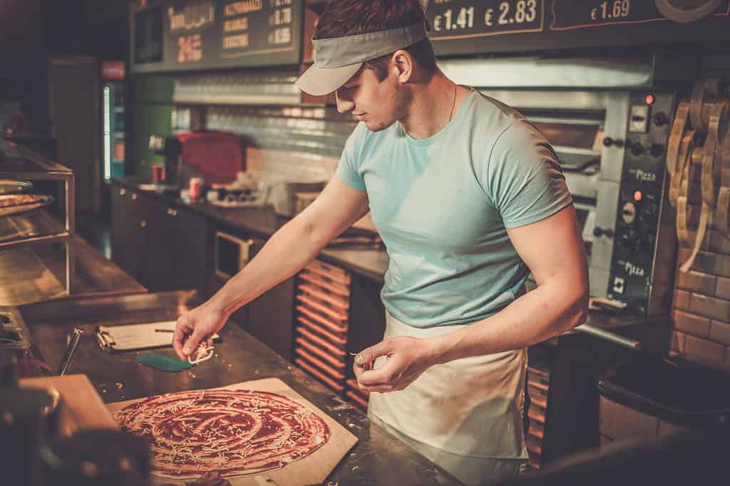 man preparing pizza - domino's franchise cost