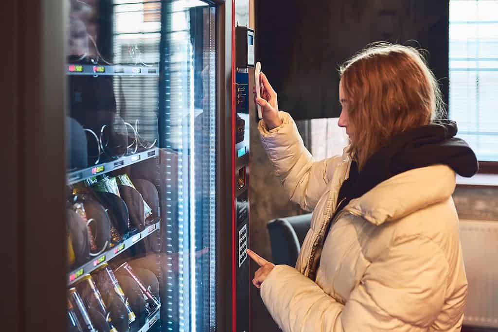 woman paying for product at vending machine, how to start a vending machine business