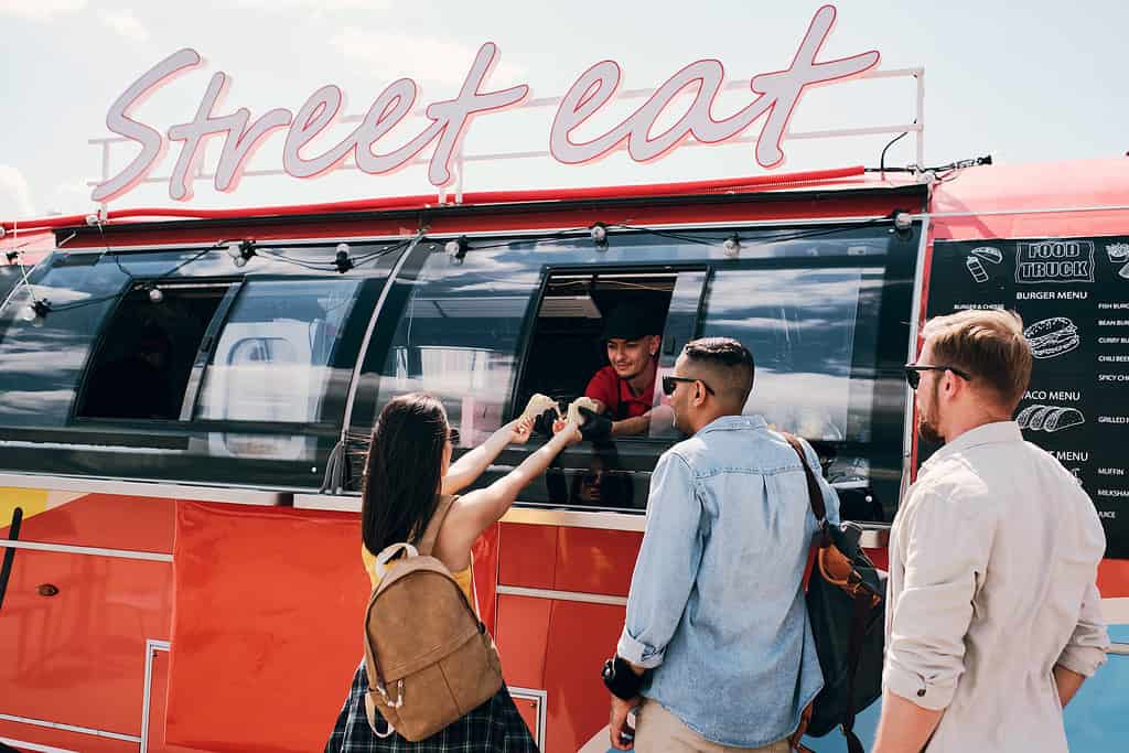 woman buying hot dog from food truck - food truck business plan